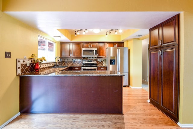 23423 Earlmist Dr, Spring, TX 77373 - kitchen featuring appliances with stainless steel finishes, a sink, a peninsula, light wood-type flooring, and tasteful backsplash