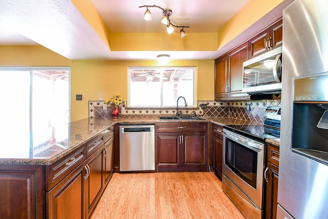 23423 Earlmist Dr, Spring, TX 77373 - kitchen featuring stainless steel appliances, a sink, a peninsula, light wood-style flooring, and backsplash