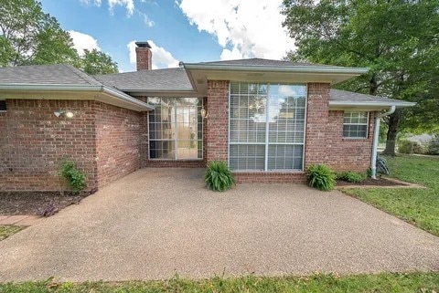 261 Colonial Cir, Athens, TX 75751 - back of property featuring brick siding, a chimney, and a patio