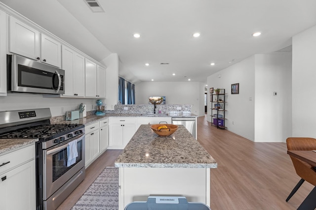 21411 Waldenburg Pl, Tomball, TX 77375 - kitchen with appliances with stainless steel finishes, light wood-type flooring, a peninsula, a kitchen island, and white cabinetry