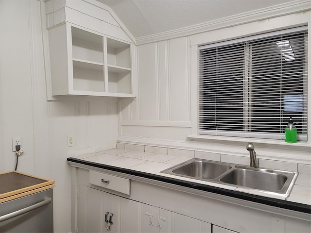 5806 Bayou Bend Ct, Houston, TX 77004 - kitchen featuring a sink, vaulted ceiling, glass insert cabinets, white cabinets, and a decorative wall