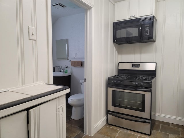 5806 Bayou Bend Ct, Houston, TX 77004 - kitchen featuring black microwave, stainless steel gas range oven, white cabinetry, a sink, and light countertops