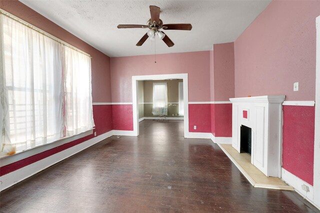 2005 Chestnut St, Houston, TX 77009 - unfurnished living room featuring a ceiling fan, wood finished floors, a fireplace with raised hearth, baseboards, and a textured ceiling