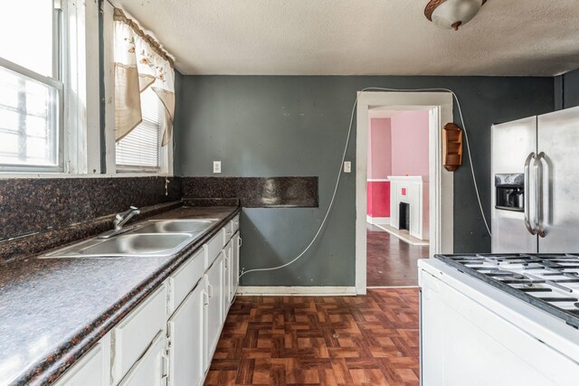 2005 Chestnut St, Houston, TX 77009 - kitchen featuring a sink, stainless steel fridge with ice dispenser, white cabinets, white gas range oven, and a textured ceiling