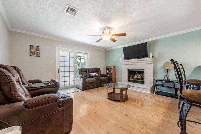 19414 Gooselake Ln, Houston, TX 77084 - living area featuring a ceiling fan, ornamental molding, light wood finished floors, a fireplace, and a textured ceiling