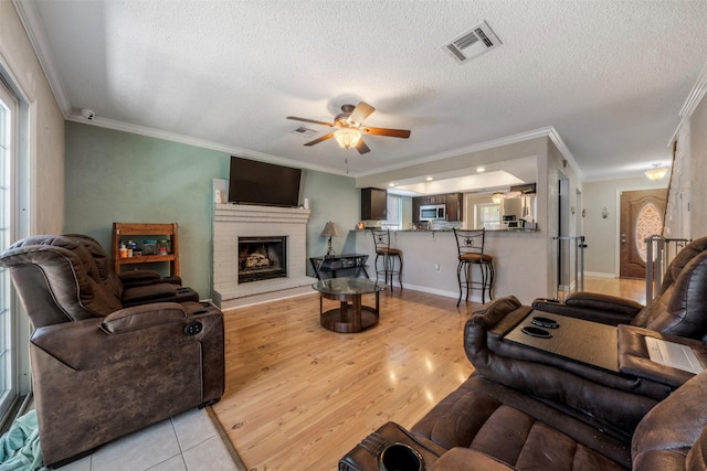 19414 Gooselake Ln, Houston, TX 77084 - living area with ornamental molding, ceiling fan, a textured ceiling, a fireplace, and light wood-style flooring