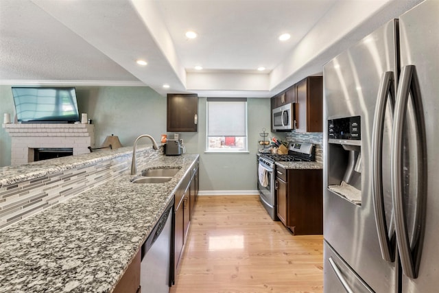 19414 Gooselake Ln, Houston, TX 77084 - kitchen with stainless steel appliances, a sink, light wood finished floors, tasteful backsplash, and dark brown cabinetry
