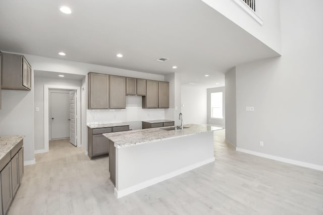 12027 Maple Oak Dr, Houston, TX 77066 - kitchen featuring a sink, light wood-style flooring, baseboards, recessed lighting, and a center island with sink