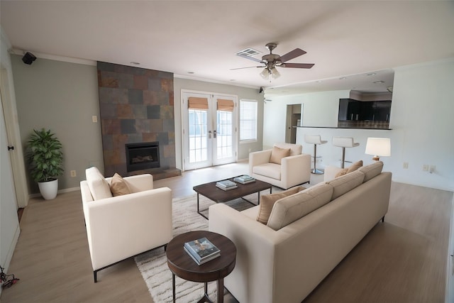 5507 W Bellfort Ave, Houston, TX 77035 - living room featuring crown molding, light wood-style floors, french doors, ceiling fan, and a large fireplace