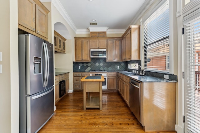 1335 Fairview Ave, Houston, TX 77006 - kitchen featuring stainless steel appliances, ornamental molding, wood finished floors, tasteful backsplash, and a center island