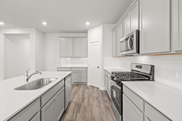 5803 Grantgrala Dr, Katy, TX 77493 - kitchen featuring appliances with stainless steel finishes, a sink, light wood-style flooring, recessed lighting, and light countertops