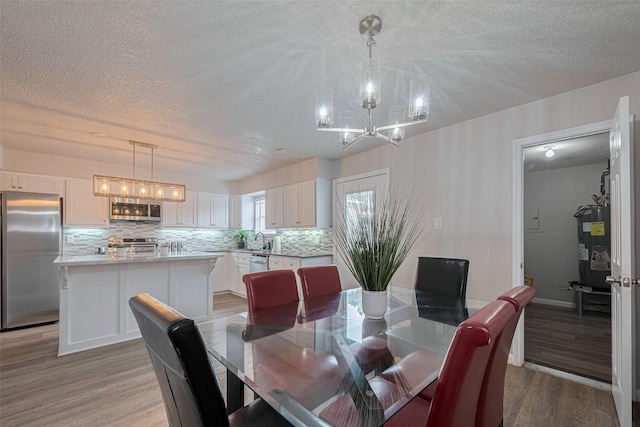 5825 Village Forest Ct, Houston, TX 77092 - dining space with a chandelier, a textured ceiling, light wood-type flooring, and water heater