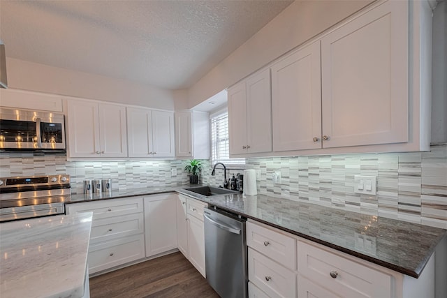 5825 Village Forest Ct, Houston, TX 77092 - kitchen with appliances with stainless steel finishes, a sink, dark stone counters, white cabinets, and a textured ceiling