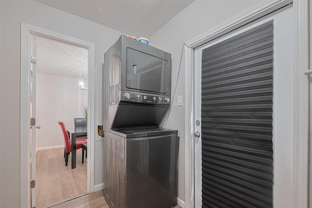5825 Village Forest Ct, Houston, TX 77092 - laundry area featuring stacked washing machine and dryer, light wood-style flooring, and baseboards