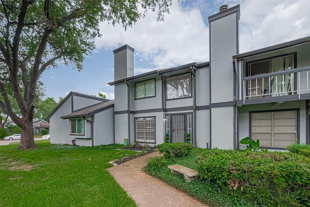 5825 Village Forest Ct, Houston, TX 77092 - back of house with a chimney, a lawn, stucco siding, and a balcony