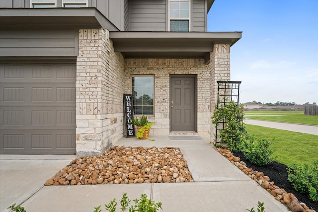 view of exterior entry featuring stone siding, a garage, and concrete driveway