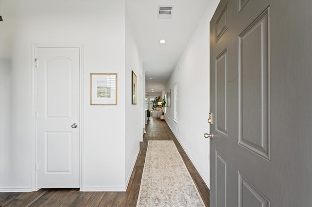 hall featuring dark wood-type flooring, recessed lighting, and baseboards