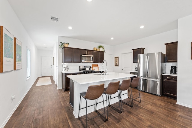 kitchen with appliances with stainless steel finishes, decorative backsplash, dark wood finished floors, light countertops, and recessed lighting