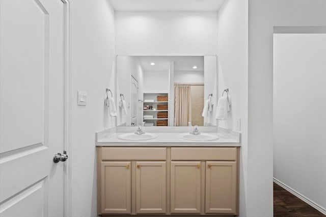 full bath featuring double vanity, wood finished floors, baseboards, and recessed lighting