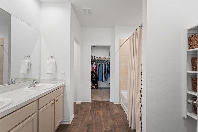 full bath featuring wood finished floors, a spacious closet, double vanity, and shower / tub combo
