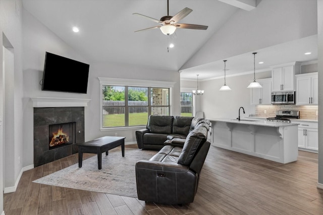 201 Patience Ave, Lindale, TX 75771 - living room with a tile fireplace, ceiling fan, wood finished floors, high vaulted ceiling, and a chandelier