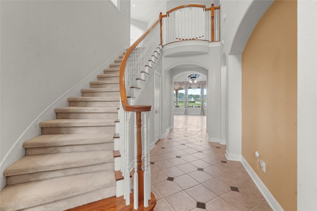6318 Goodlowe Park, Sugar Land, TX 77479 - stairs featuring arched walkways, tile patterned flooring, a towering ceiling, a ceiling fan, and baseboards