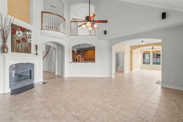 6318 Goodlowe Park, Sugar Land, TX 77479 - unfurnished living room featuring a ceiling fan, light tile patterned flooring, a premium fireplace, a high ceiling, and baseboards