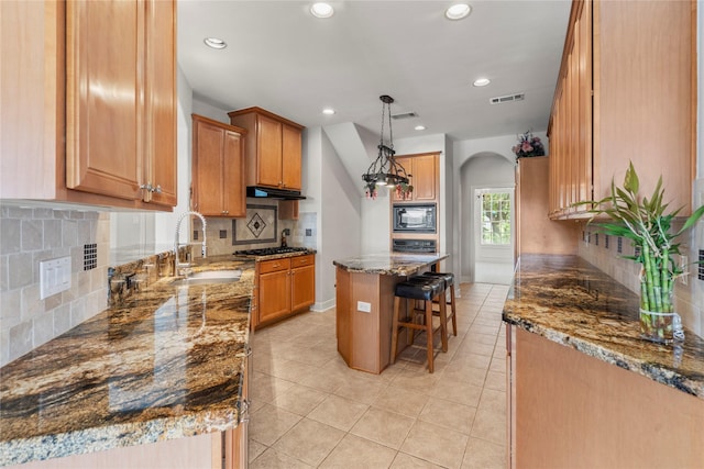 6318 Goodlowe Park, Sugar Land, TX 77479 - kitchen with black microwave, a sink, a breakfast bar, arched walkways, and stone counters
