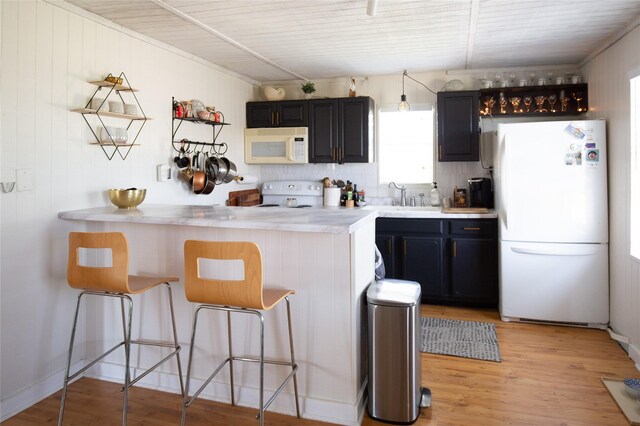 16535 Jamaica Inn Rd, Jamaica Beach, TX 77554 - kitchen with white appliances, a breakfast bar area, light countertops, a sink, and a peninsula