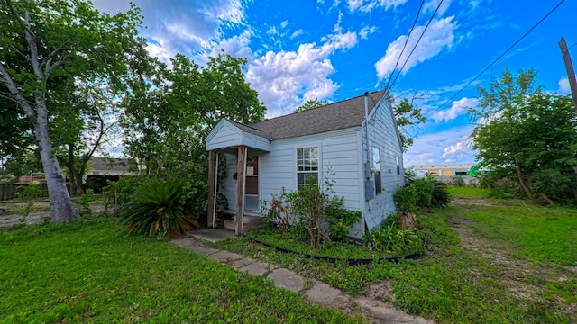 view of front facade with roof with shingles and a front yard
