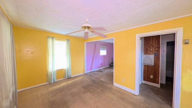 empty room featuring a ceiling fan, baseboards, carpet, and crown molding