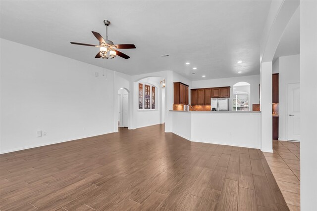 3031 Clover Trace Dr, Spring, TX 77386 - unfurnished living room featuring arched walkways, wood finished floors, a ceiling fan, recessed lighting, and a sink