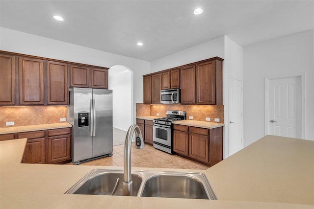 3031 Clover Trace Dr, Spring, TX 77386 - kitchen featuring appliances with stainless steel finishes, a sink, recessed lighting, arched walkways, and backsplash