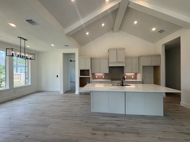 16163 Rustling Woods Rd, Conroe, TX 77302 - kitchen featuring gray cabinets, beam ceiling, a large island, backsplash, and light countertops