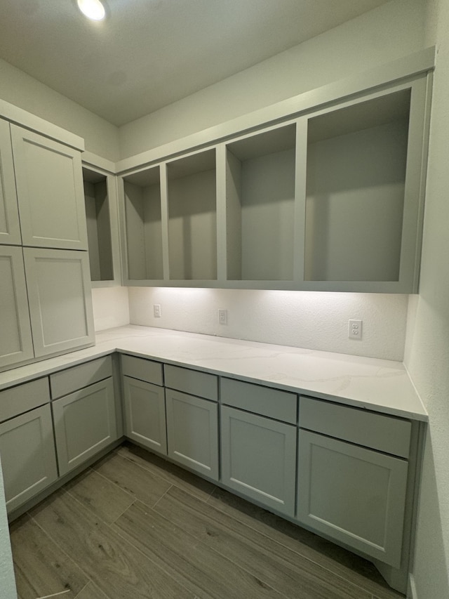 16163 Rustling Woods Rd, Conroe, TX 77302 - kitchen with gray cabinets, dark wood-style floors, and light stone countertops