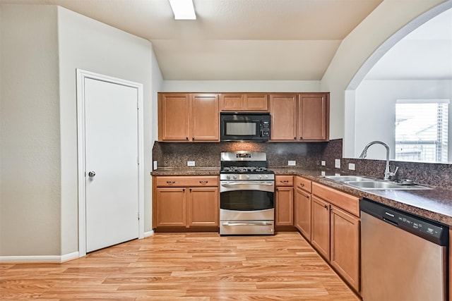 5212 Mcgrath Dr, Alvin, TX 77511 - kitchen featuring appliances with stainless steel finishes, a sink, arched walkways, light wood-style flooring, and lofted ceiling