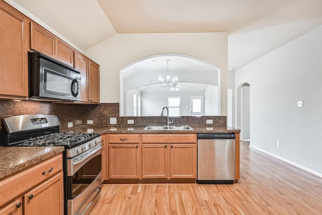 5212 Mcgrath Dr, Alvin, TX 77511 - kitchen featuring appliances with stainless steel finishes, a sink, arched walkways, lofted ceiling, and a chandelier