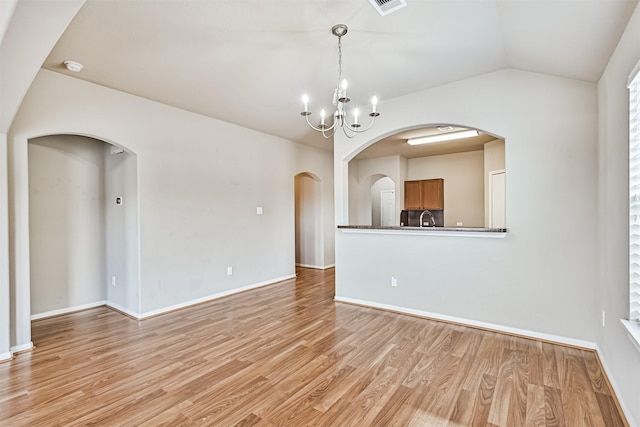 5212 Mcgrath Dr, Alvin, TX 77511 - unfurnished living room with a sink, arched walkways, a chandelier, light wood-style flooring, and vaulted ceiling