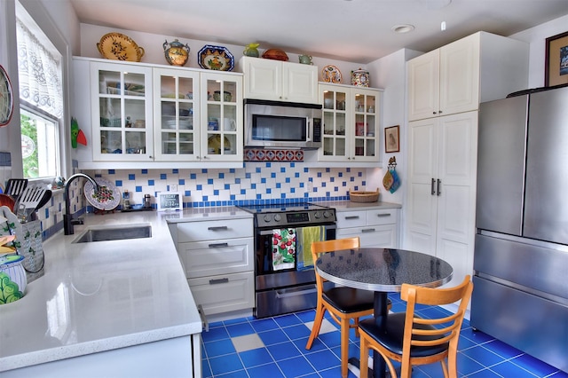 1119 E 7th 1/2 St, Houston, TX 77009 - kitchen with stainless steel appliances, a sink, white cabinets, tasteful backsplash, and glass insert cabinets