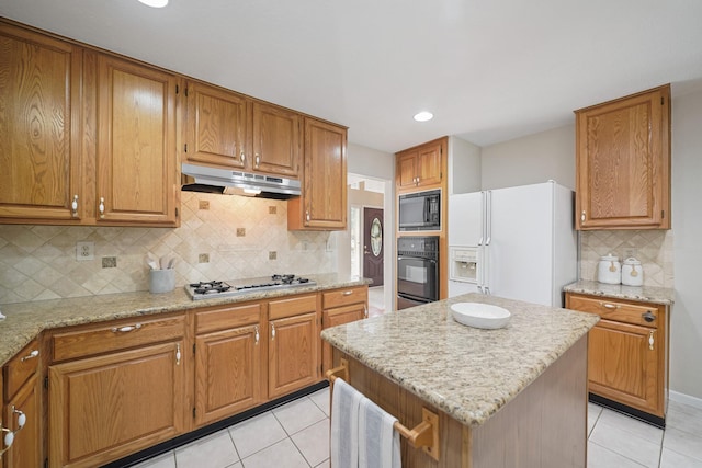 8602 Canyon Pine Dr, Spring, TX 77379 - kitchen featuring black appliances, under cabinet range hood, light tile patterned flooring, brown cabinets, and recessed lighting