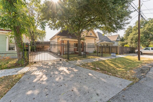 2009 Chestnut St, Houston, TX 77009 - view of property hidden behind natural elements featuring a fenced front yard, a gate, and concrete driveway