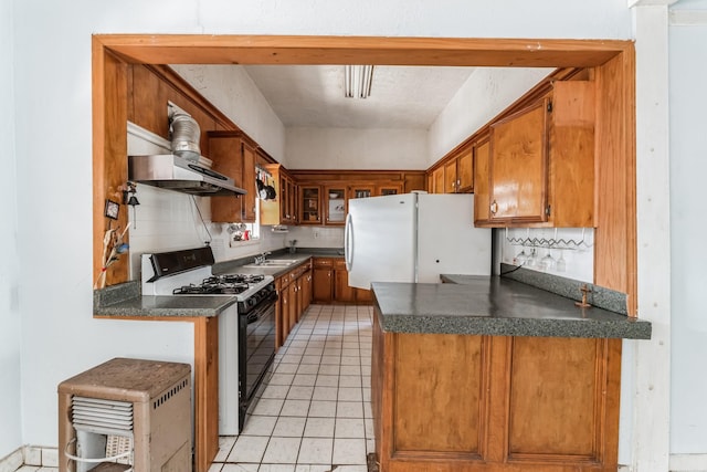 2009 Chestnut St, Houston, TX 77009 - kitchen featuring black gas stove, freestanding refrigerator, extractor fan, dark countertops, and a sink