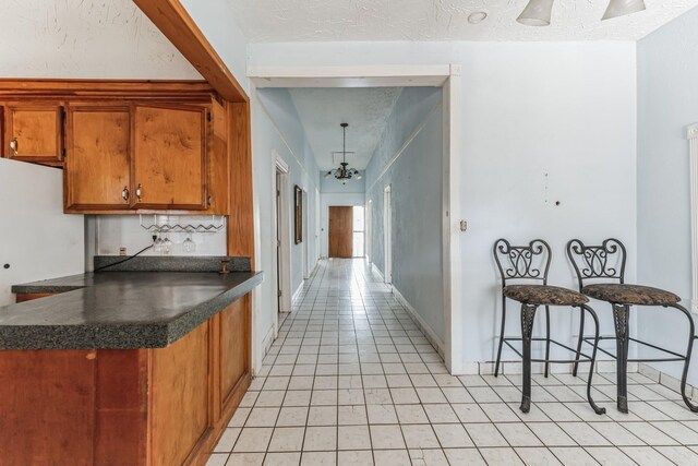 2009 Chestnut St, Houston, TX 77009 - kitchen featuring dark countertops, brown cabinets, light tile patterned flooring, a chandelier, and tasteful backsplash