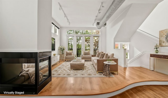 2436 Bissonnet St Unit 8, Houston, TX 77005 - living area featuring wood finished floors, a multi sided fireplace, rail lighting, and baseboards