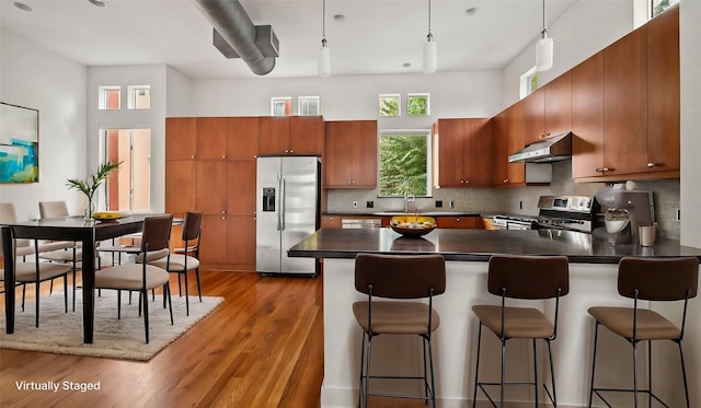 2436 Bissonnet St Unit 8, Houston, TX 77005 - kitchen featuring appliances with stainless steel finishes, under cabinet range hood, dark countertops, a peninsula, and light wood-type flooring