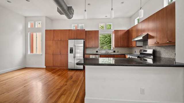 2436 Bissonnet St Unit 8, Houston, TX 77005 - kitchen with appliances with stainless steel finishes, under cabinet range hood, light wood-style floors, brown cabinetry, and tasteful backsplash
