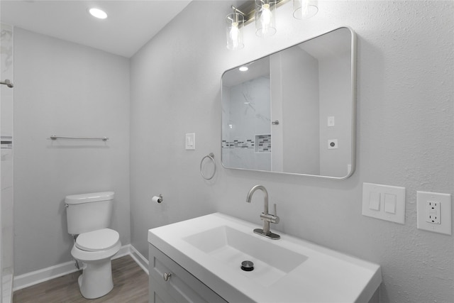 9827 Shive Dr, Houston, TX 77078 - full bath featuring wood finished floors, toilet, vanity, baseboards, and recessed lighting
