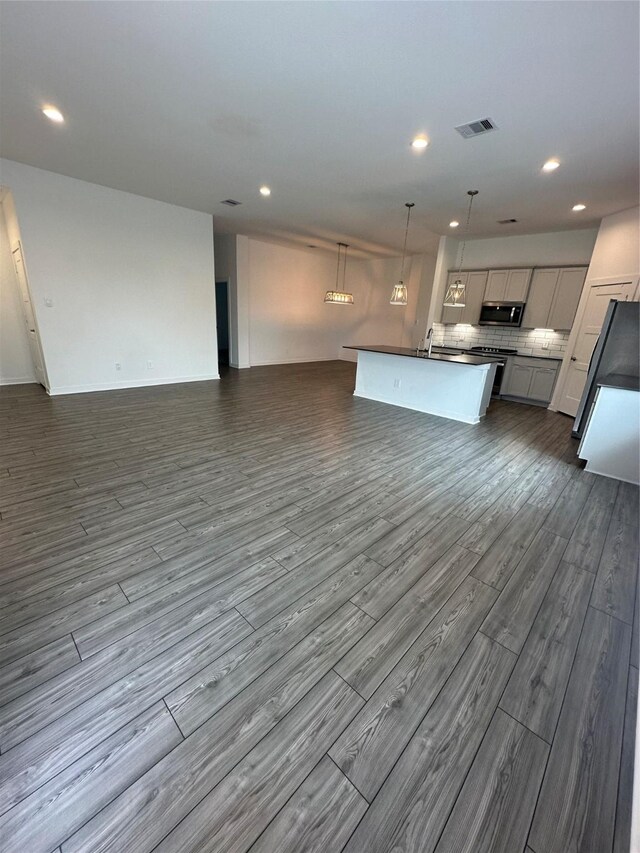 14007 Valley Creek Ct, Conroe, TX 77384 - kitchen featuring open floor plan, stainless steel microwave, dark countertops, dark wood-style flooring, and recessed lighting