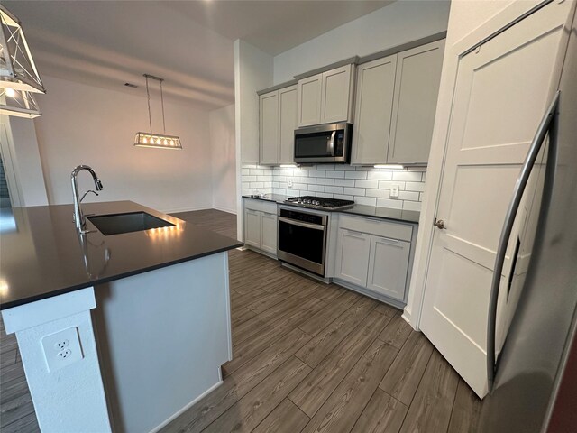 14007 Valley Creek Ct, Conroe, TX 77384 - kitchen with appliances with stainless steel finishes, a sink, dark countertops, backsplash, and dark wood-type flooring