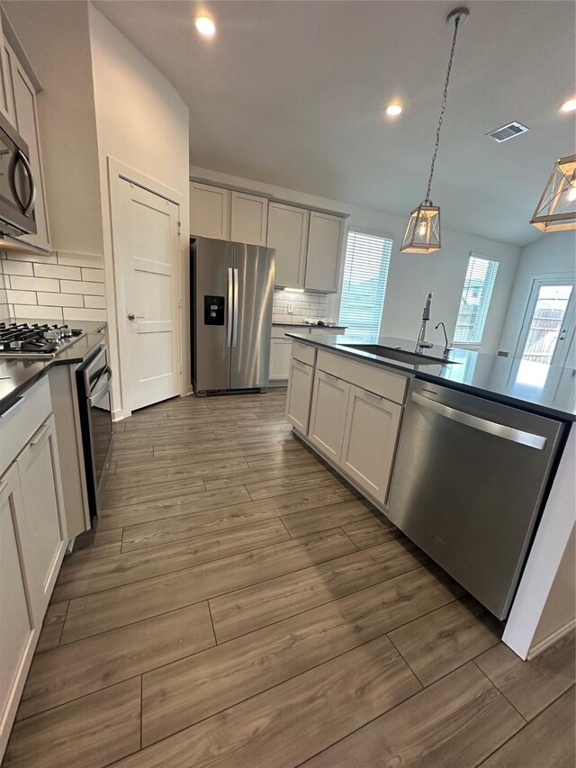 14007 Valley Creek Ct, Conroe, TX 77384 - kitchen featuring stainless steel appliances, dark countertops, a sink, tasteful backsplash, and plenty of natural light